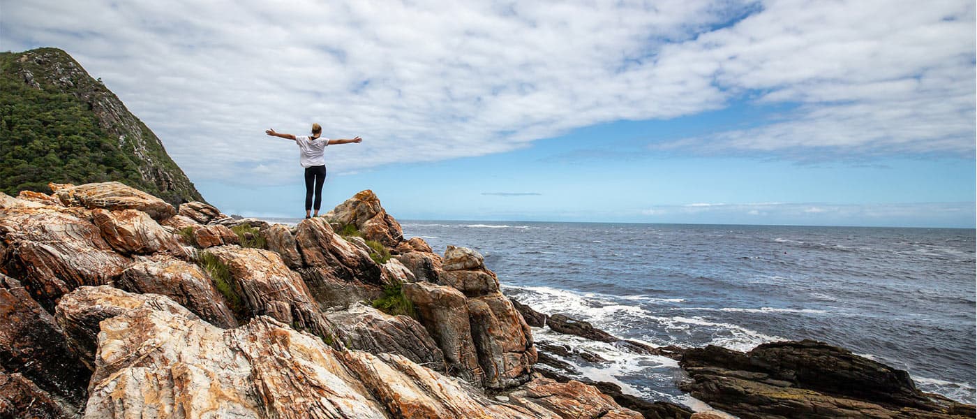 woman arms open on rock breathing facing ocean pranayama pranayam yoga breathing