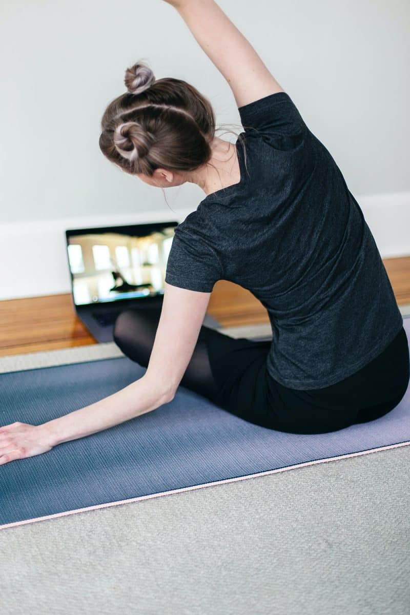 Young woman stretching in from t of computer benefits taking yoga course training online