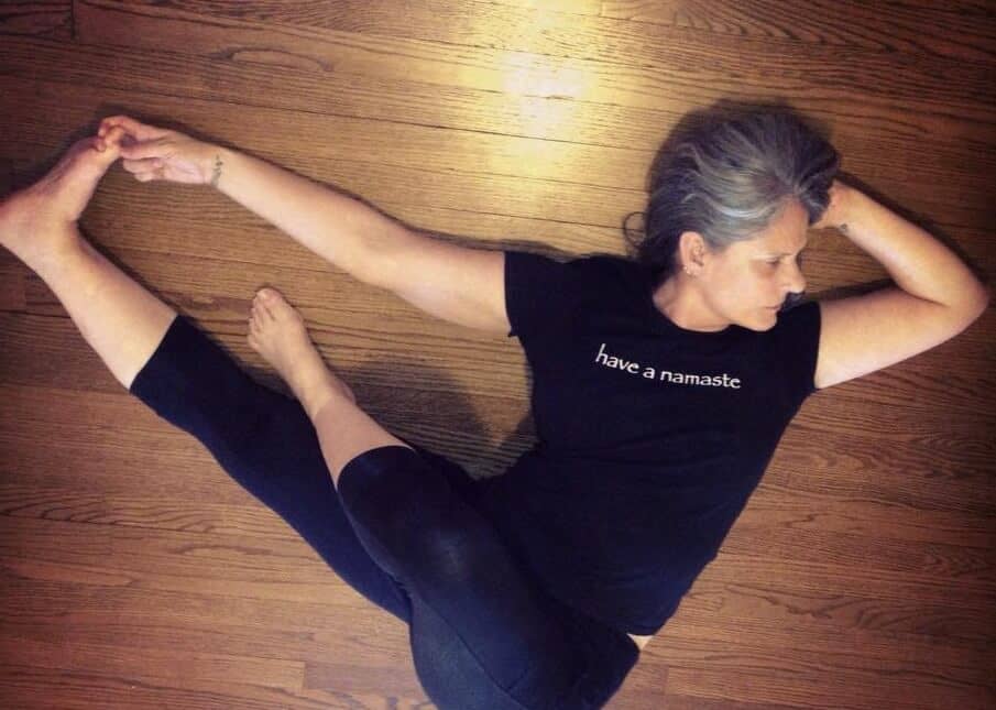 Woman laying on wooden floor Cyndi lee yoga teacher