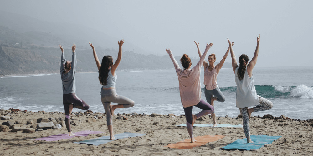 Group of womans practising yoga on the beach Outdoor yoga Chicago New York San Francisco Los Angeles Seattle