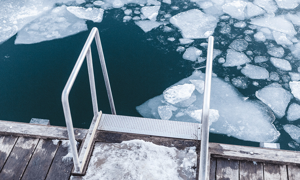 Wooden deck with a set of stairs on a lake with ice that is melting